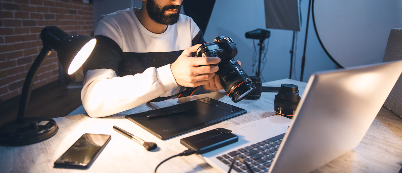 photographer-hand-camera-with-computer-table_218381-3115